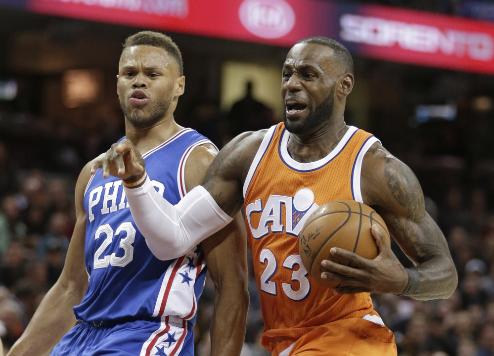 Cleveland's LeBron James, right, drives to the basket against the 76ers' Justin Anderson during the first half of their game in Cleveland on Friday night. The Cavaliers won 122-105 to halt a three-game losing streak.