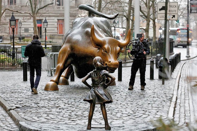 A camera man films the statue of a girl facing the Wall St. Bull in the New York financial district.