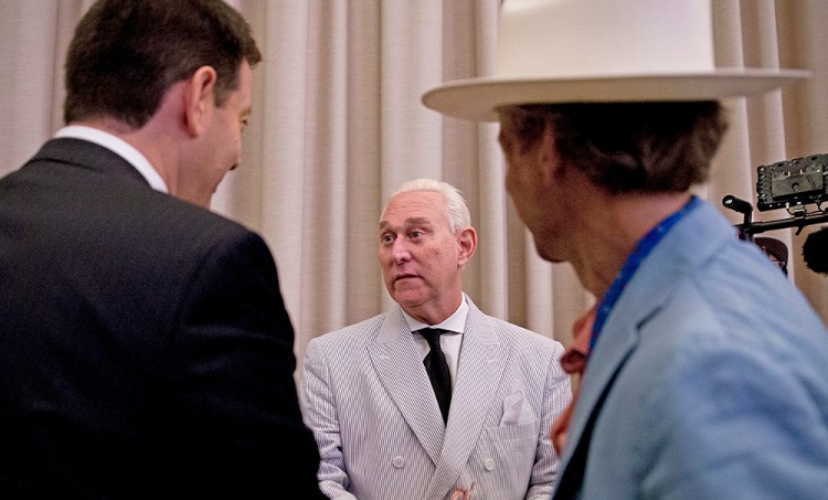 Roger Stone, center, an adviser to Donald Trump, speaks to reporters in New York. He says he's retained two attorneys to explore whether he can compel the government to "either charge me or admit they have no case whatsoever."