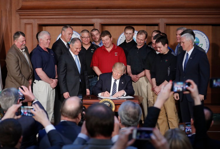 President Trump, accompanied by EPA Administrator Scott Pruitt, third from left, and Vice President Mike Pence, right, signs an executive order on Tuesday at the EPA headquarters in Washington.