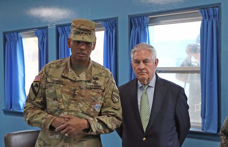 Secretary of State Rex Tillerson meets with U.S. Gen. Vincent K. Brooks, commander of the United Nations Command, Combined Forces Command and United States Forces Korea, last Friday in the village of Panmunjom, which has separated the two Koreas since the Korean War. In the background, a North Korean soldier takes a photograph through the window. 