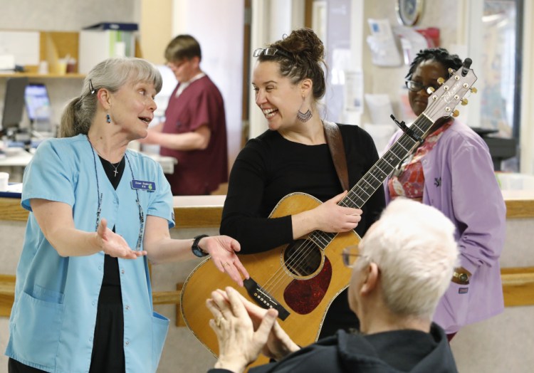 Singer-songwriter Sorcha Cribben-Merrill shares a laugh with nurse Susan Stadnicki and a resident following a recent performance at the memory loss unit at Saint Joseph's Rehabilitation and Residence in Portland. Below, Cribben-Merrill and Stadnicki entertain a patient during her visit.