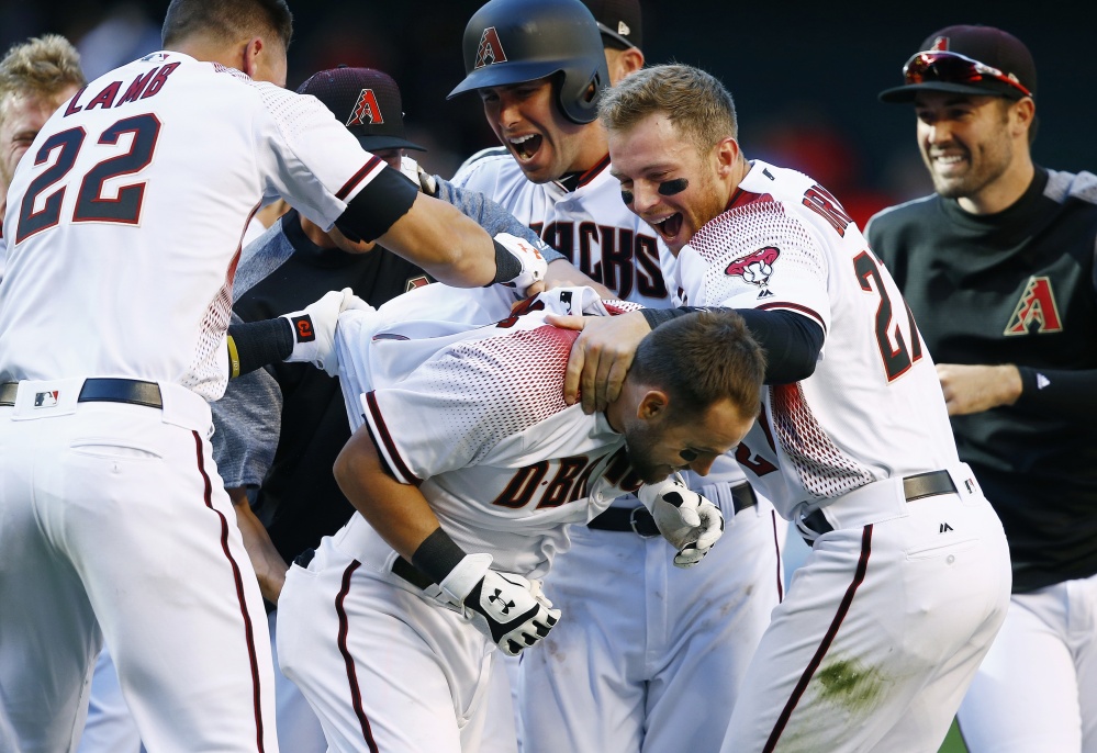 Arizona's Chris Owings, front, celebrates his walk-off single with Jake Lamb, left, Paul Goldschmidt, second from left, Brandon Drury, second from right, and Robbie Ray after the Diamondbacks' 6-5 win over San Francisco in a season opener Sunday in Phoenix.