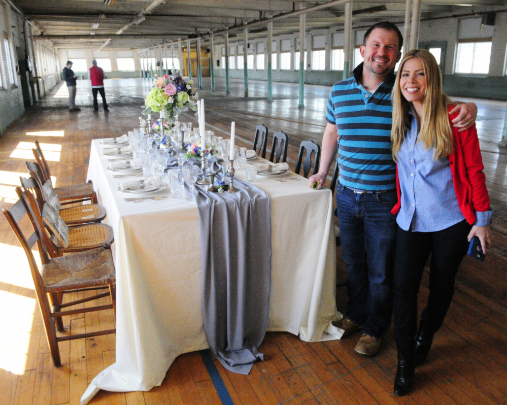 John Butterfield of Leaf and Petal's Flower Design and venue co-owner Veronica Carbona stand beside a table they decorated Thursday at Penthouse V on the fifth floor of the Winthrop Commerce Center, formerly the Carleton Woolen Mill.