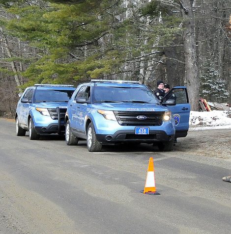 Two Maine State Police troopers consult with each other outside a residence on Winnecook Road in Burnham while investigating the death of Joyce Wood on Sunday. A pair of boots lie in the road in the foreground.
