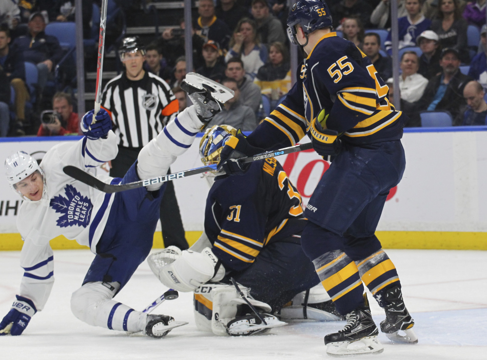 Buffalo defenseman Rasmus Ristolainen, right, knocks down Toronto forward Zach Hyman during the second period of a 4-2 win Monday by the Maple Leafs at Buffalo, N.Y.