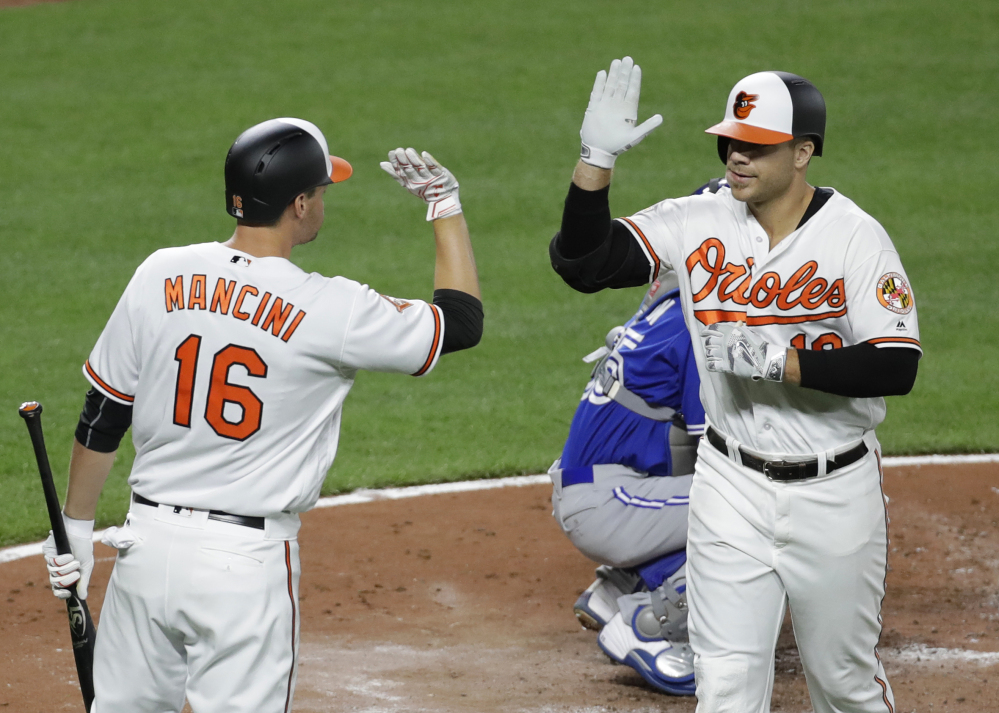 Baltimore's Chris Davis, right, high-fives teammate Trey Mancini after hitting a solo home run during the fourth inning of the Orioles' 3-1 win at home against Toronto on Wednesday night.