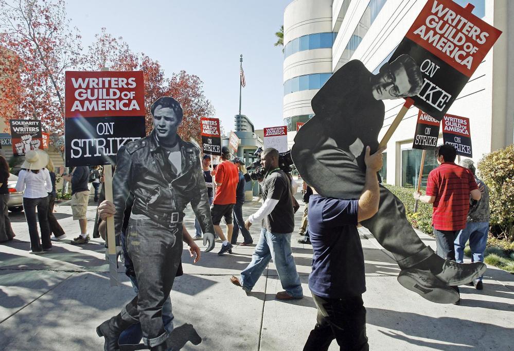 In 2007, striking writers carry life-sized photos of legendary actors, Marlon Brando, left, and James Dean to express their support to members of the Writers Guild of America. While television enjoys a Golden Age, the WGA claims the writers aren't being paid like it.