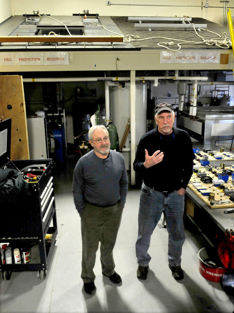 Solar Design instructors Rich Roughgarden, left, and Keven Vachon speak in front of a solar panel roof installation lab at Kennebec Valley Community College in Fairfield on Thursday.