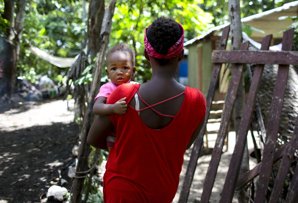 Janila Jean, 18, carries her daughter as she walks to her friend's house in Jacmel, Haiti. Jean said she was a 16-year-old virgin when a U.N. peacekeeper from Brazil lured her to the U.N. compound with a smear of peanut butter on bread, then raped her at gunpoint and left her pregnant.