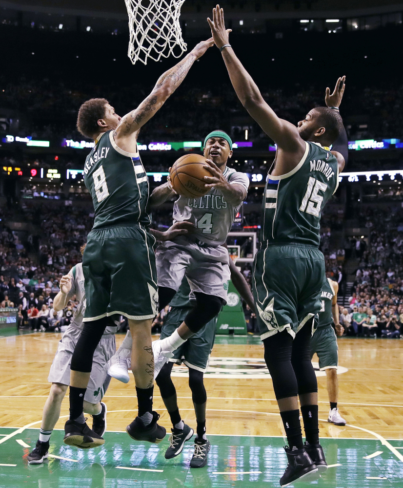 Celtics guard Isaiah Thomas, 4, threads between Bucks guard Matthew Dellavedova, 8, and center Greg Monroe on a drive to the basket during the first quarter Wednesday night in Boston.