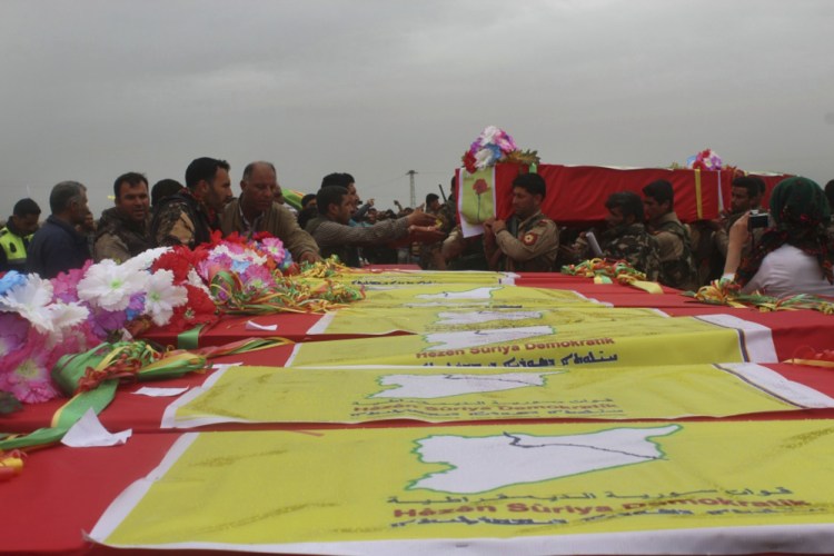 This photo provided by Hawar News Agency, a Kurdish-run news agency, which has been authenticated based on its contents and other Associated Press reporting, shows fighters from the predominantly-Kurdish Syrian Democratic Forces carrying the coffins of their comrades, who were killed Tuesday by a misdirected airstrike by the U.S.-led coalition, during their funeral procession, in Tal al-Abyad, northeast Syria, on Thursday.