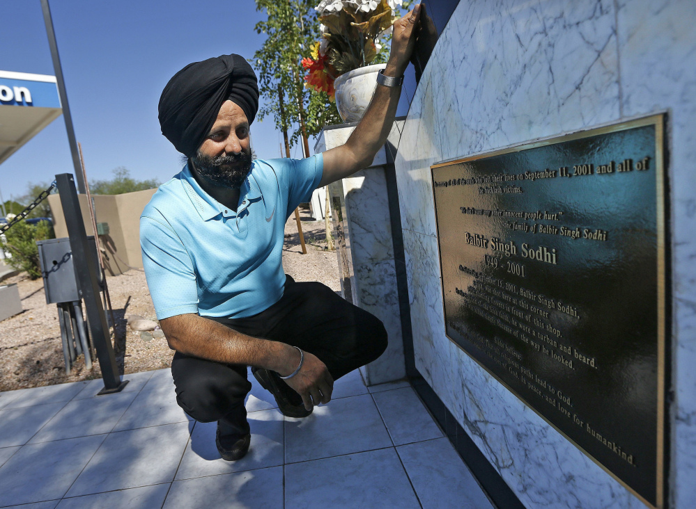 Rana Singh Sodhi kneels near his service station last summer in Mesa, Ariz., next to a memorial for his brother, Balbir Singh Sodhi, who was murdered in the days after the Sept. 11 terrorist attacks by a man who said he wanted to kill Muslims.