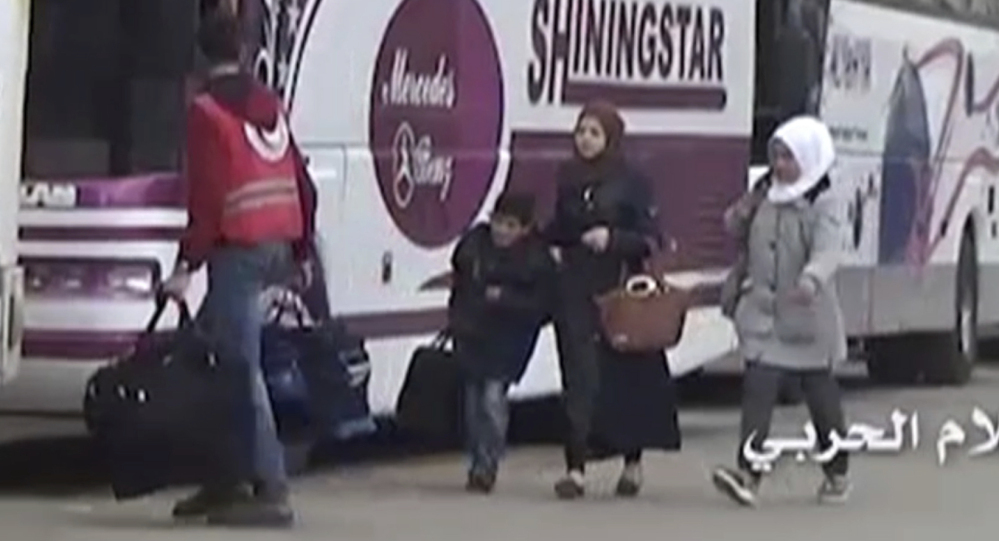 Video provided by the Syrian Central Military Media shows a Syrian Red Arab Crescent volunteer carrying bags of a family heading to a bus as they leave the town of Madaya.