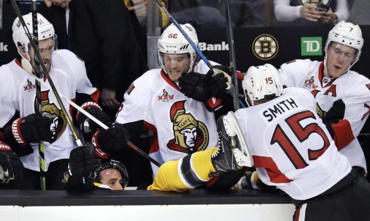 Ottawa Senators center Zack Smith (15) checks Boston Bruins center Ryan Spooner into the Senators bench during the third period in Game 3 of a first-round NHL hockey playoff series in Boston.