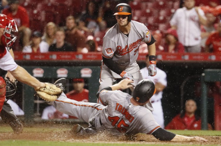 Mark Trumbo of the Baltimore Orioles avoids a tag by Cincinnati catcher Stuart Turner to score the go-ahead run Thursday night on a single by J.J. Hardy in the 10th inning. The Orioles, who will meet the Boston Red Sox this weekend, collected a 2-1 victory.