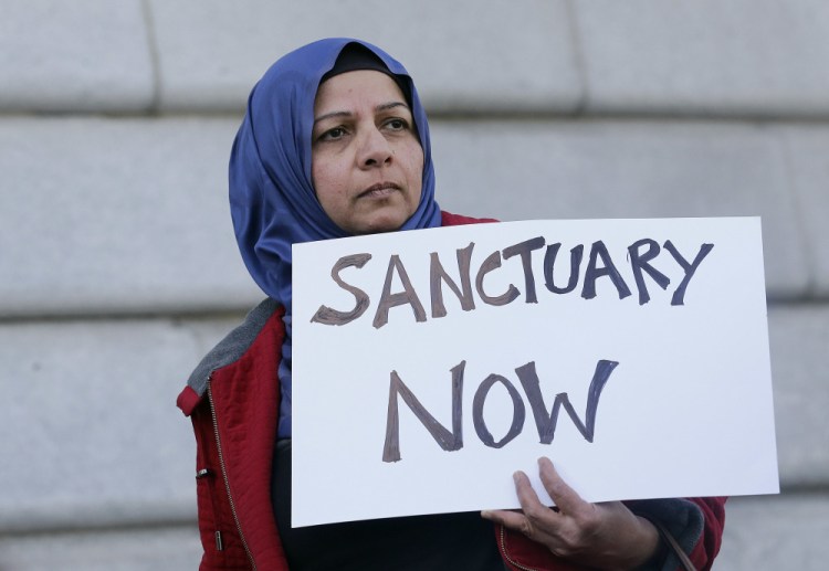 A woman holds a sign at a rally outside of City Hall in San Francisco in January. The Justice department is demanding that nine communities prove they are complying with an immigration law in order to continue receiving coveted law enforcement grant money.