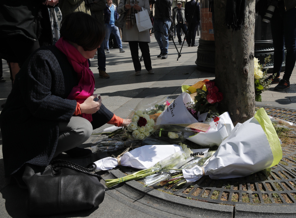 A womans lay flowers Friday at the place where a police officer was killed by a gunman on Thursday on the Champs Elysees boulevard in Paris.