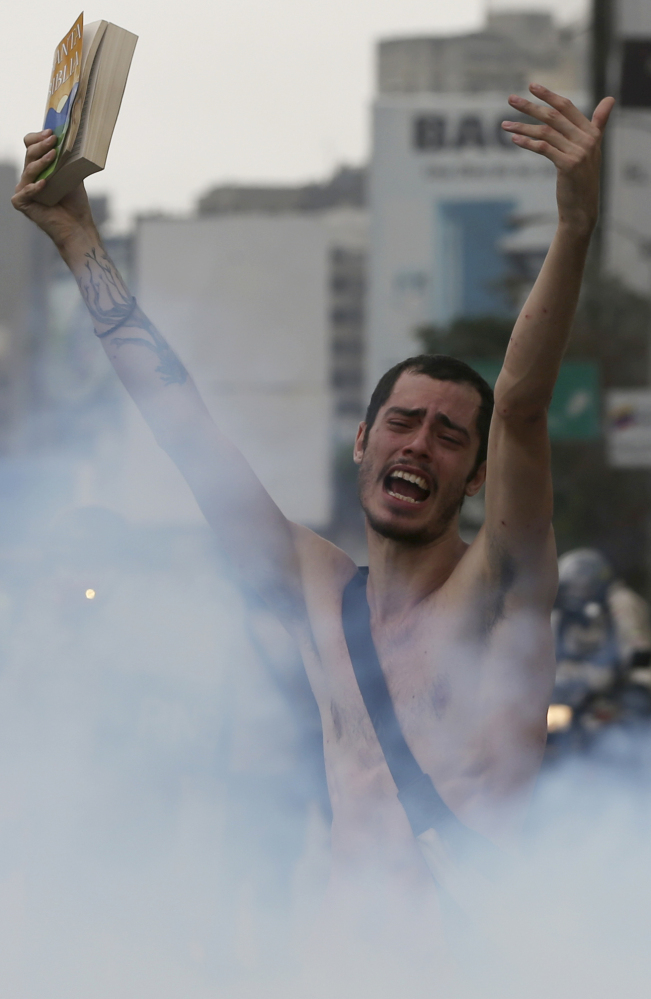 A protester holds a bible in a cloud of tear gas during a march in Caracas, Venezuela, on Thursday.