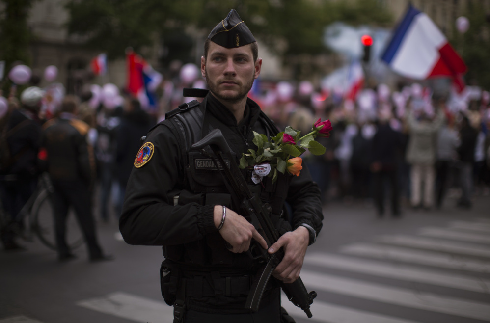 A French riot police officer carries flowers given to him by a protester who demonstrated with others in what was described as a march of support for all French security forces.