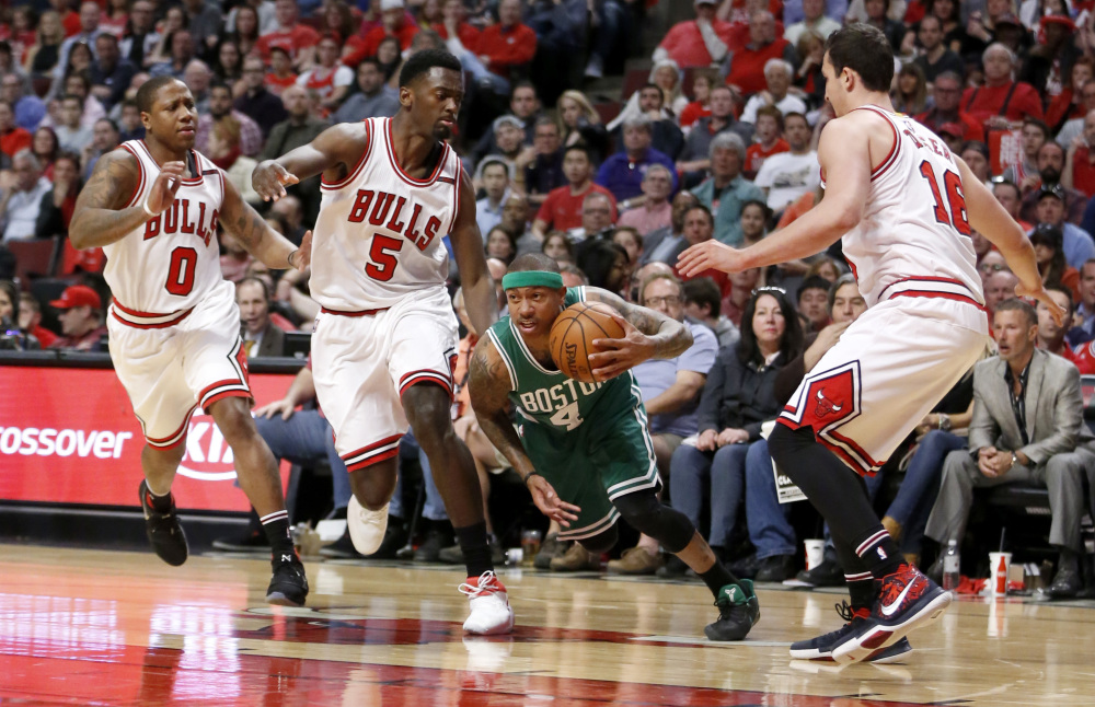 Boston's Isaiah Thomas dribbles through the Chicago defense of Isaiah Canaan, left, Bobby Portis, 5, and Paul Zipser during the first half of the Celtics' 104-95 win Sunday in Game 4 of their first-round series in Chicago. The series is tied 2-2.