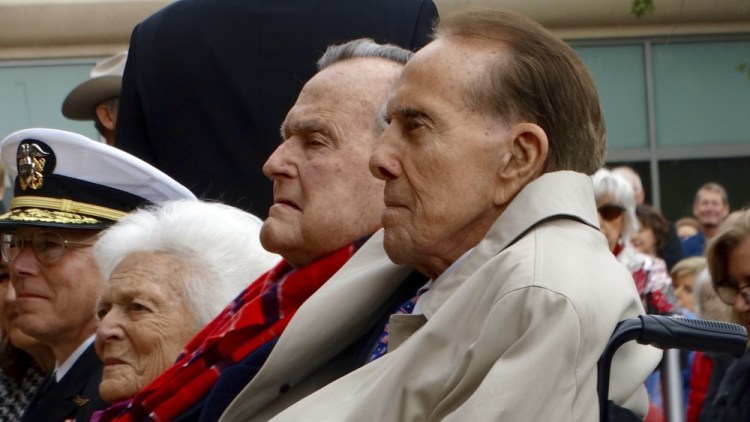 Former Sen. Bob Dole, right, former President George H.W. Bush and former First Lady Barbara but sit together at a Pearl Harbor commemoration ceremony at the Bush Library Center in College Station, Texas, in December. A spokesman for former President Bush said Monday that the nation's 41st president will remain in a Houston hospital for a few more days of observation while he recovers from a mild case of pneumonia.