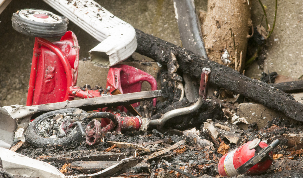 A tricycle and a fire extinguisher are among the detritus Tuesday in front of 94 Mount Vernon Ave. in Augusta. The building is expected to be demolished this week.