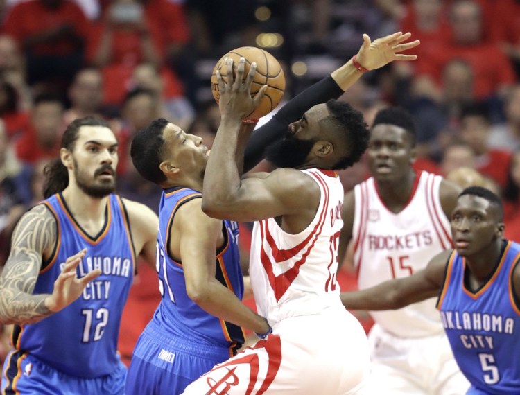 Houston's James Harden gets smacked by Oklahoma City's Andre Roberson as he drives toward the basket in Tuesday's game at Houston.