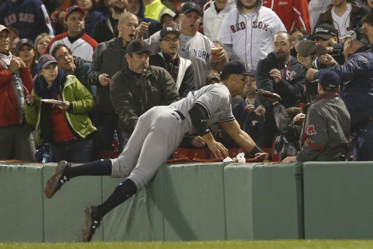 Aaron Judge of the Yankees dives into the stands to catch a foul ball hit by Boston's Xander Bogaerts in the third inning Wednesday night at Fenway Park.