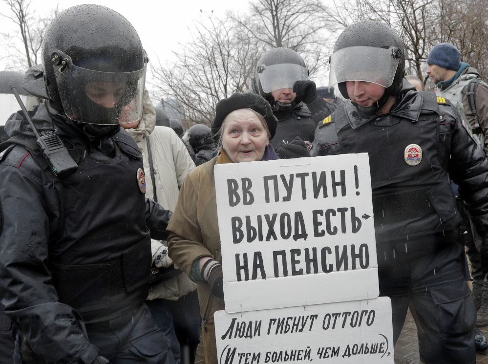 Police detain a participant of an unauthorized rally in St. Petersburg, Russia, on Saturday. A poster reads "Putin, you can retire!"
