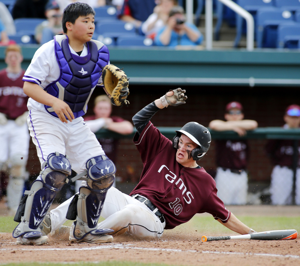 Nolan Brown of Gorham slides safely across the plate in the sixth inning as Deering catcher Princehoward Yee waits for the throw.