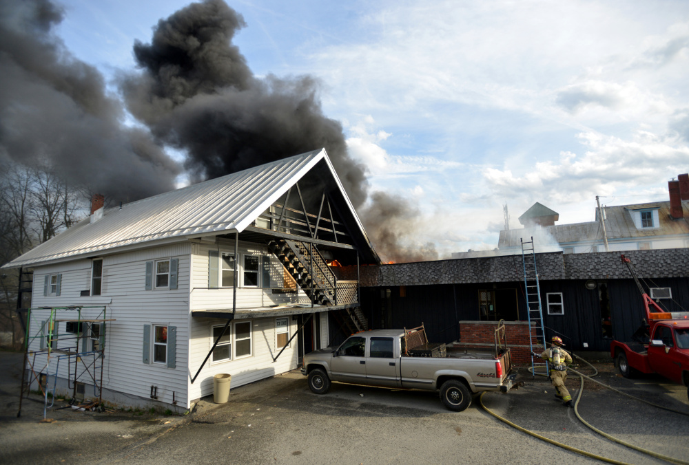 Firefighters battle a fire that spread to a second building on College Avenue in Waterville on Saturday.