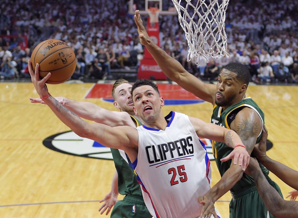 Los Angeles Clippers guard Austin Rivers, center, shoots as Utah Jazz forward Gordon Hayward, left, and forward Derrick Favors defend during the first half in Game 7 of an NBA basketball first-round playoff series, Sunday, April 30, 2017, in Los Angeles. (AP Photo/Mark J. Terrill)