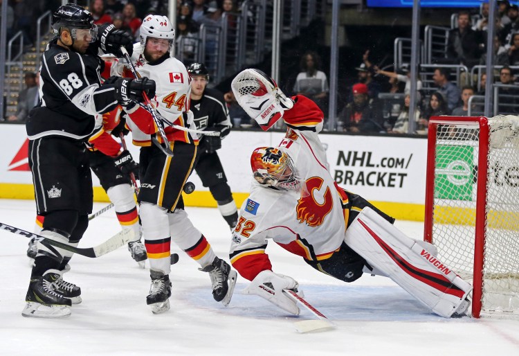 Calgary Flames goalie Jon Gillies of South Portland stretches to protect the goal, with defenseman Matt Bartkowski and Los Angeles Kings right winger Jarome Iginia in the mix during the second period Thursday night in Los Angeles.
