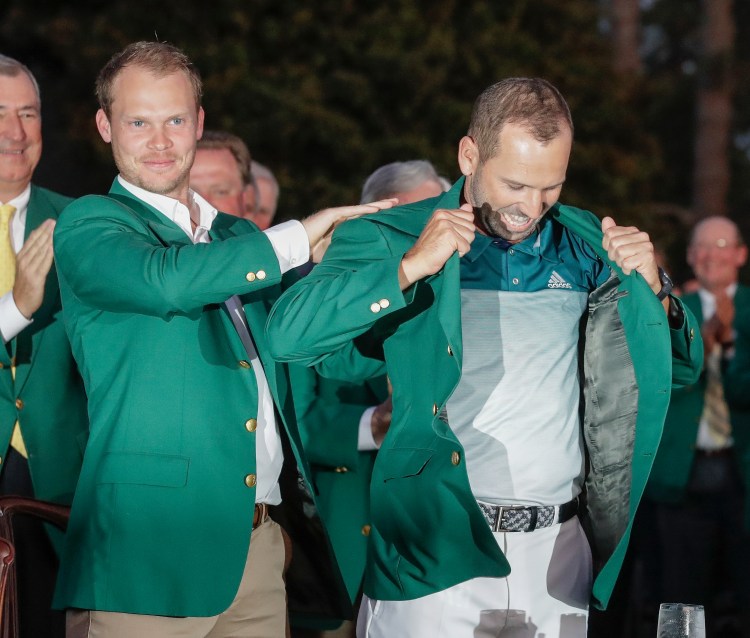 Danny Willett of England puts a green jacket on Sergio Garcia after the Masters on Sunday. It was Garcia's first major championship.