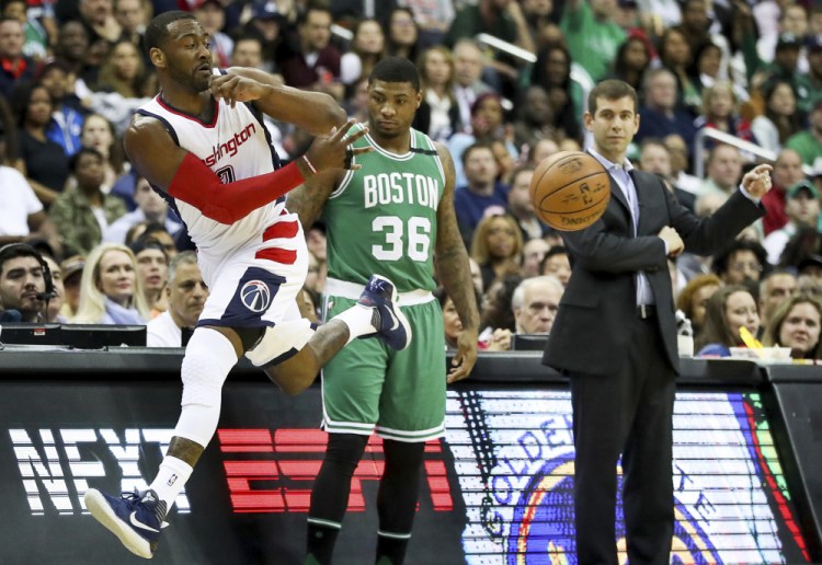 Celtics guard Marcus Smart and Coach Brad Stevens watch as Washington's John Wall  jumps out of bounds to save a loose ball during the first half Thursday night in Washington.