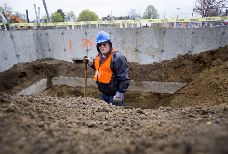 Paul Auger, a historian and teacher from Sanford, stands in a hole at a construction site on Main Street where remains from an old gravesite have been found.
