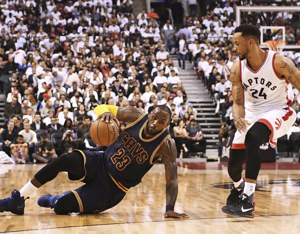 Cavaliers forward LeBron James slips on the floor as Raptors guard Norman Powell looks on during Friday's second half.