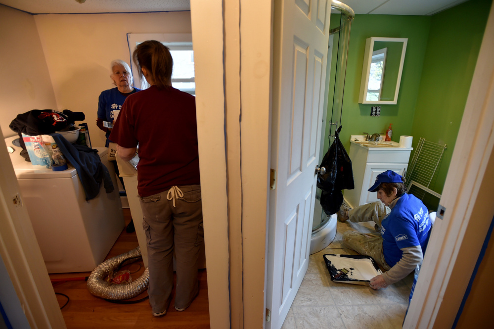 Volunteers work in the laundry room and a bathroom at 22 Water St. National Women Build Day invites women to help families build stability and independence through housing.