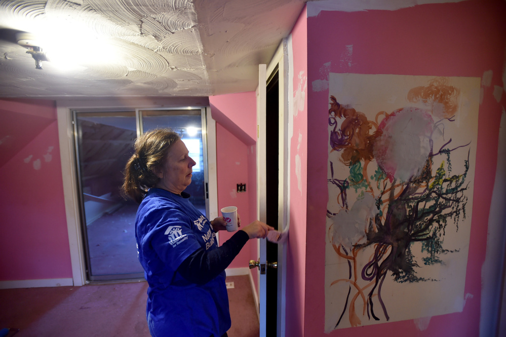 Lynn Twithell paints an upstairs bedroom Saturday while volunteering with Habitat for Humanity on National Women Build Day at 22 Water St. in Oakland.