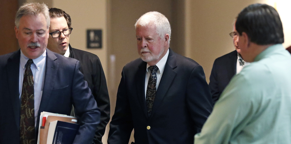 Arthur Peekel, center, a former admissions officer at Phillips Exeter Academy, follows his lawyer Philip Utter, left, past reporters after a court hearing Friday in Brentwood, N.H.