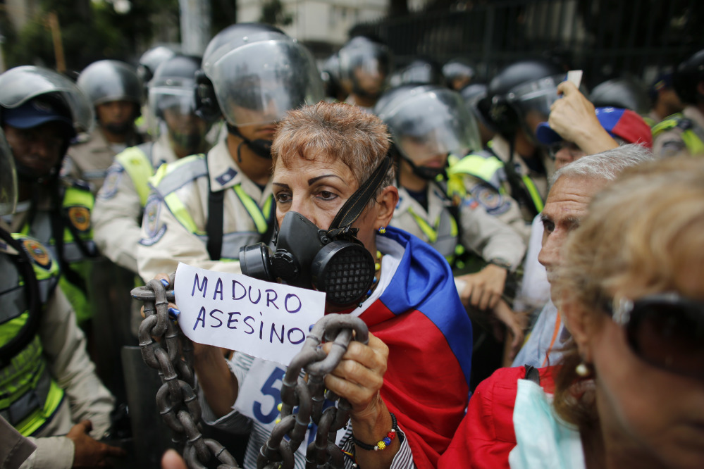 A woman holds a handwritten message that reads in Spanish: "Maduro Murderer" during a protest against President Nicolas Maduro in Caracas, Venezuela, on Friday.