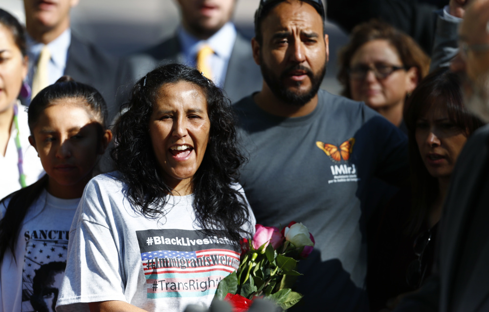 Jeanette Vizguerra, left, leaves a church Friday where she lived to avoid immigration authorities for the past three months. She and Arturo Hernandez, center, are both Mexican immigrants who have been granted two-year deportation delays.