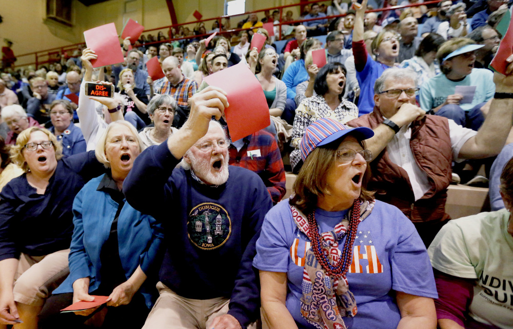 Attendees hold up their red signs to show their disapproval of Rep. Rod Blum's, R-Iowa, answer to a question during a town hall in Dubuque, Iowa, last week.