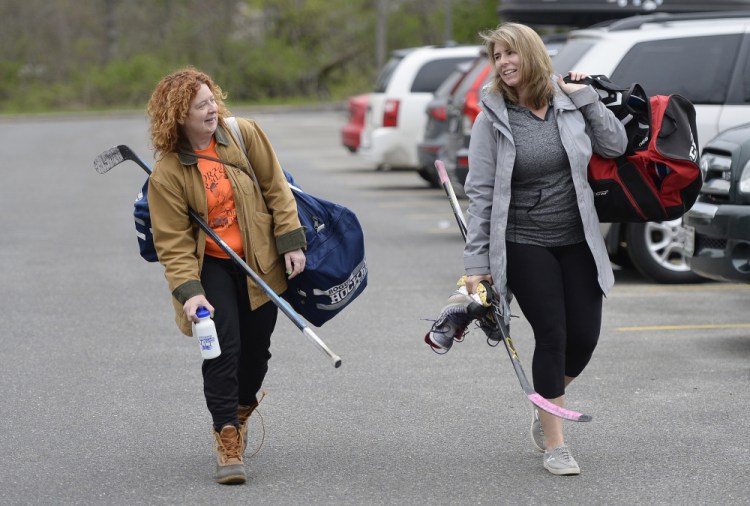 Sally Morris and Jill Piker head into Family Ice Center in Falmouth last week to play with the Morning Hockey Society. There are no officials, no coaches and generally no fans, but there is plenty of social time and exercise, members say.