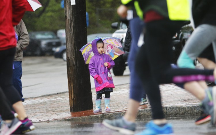 Bella Laflin, 3, of Biddeford holds a princess umbrella while watching runners' legs pass by at the start of the Mother's Day 5K in Portland. Bella was with her mom, Erin Laflin, and grandfather, Kirk Laflin of South Portland to see her dad, Derek, running in the race.