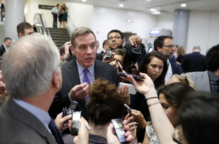 Sen. Mark Warner, D-Va., is surrounded by reporters as he walks on Capitol Hill in Washington on Wednesday. The top Democrat on the Intelligence Committee, Warner said the panel invited former FBI director James Comey to testify in open and closed sessions.