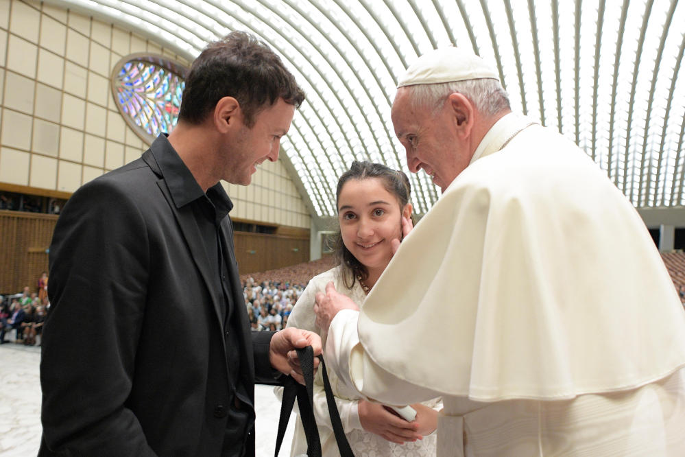 Pope Francis greets Brenda, no last name available, from Argentina, who suffers from juvenile Huntington's Disease, as she is accompanied by Argentine singer Axel during an audience with Huntington's Disease families in the Paul VI Hall at the Vatican on Thursday.
