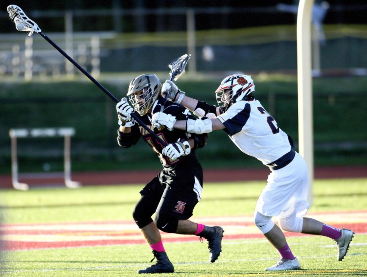 Cameron Houde of Thornton Academy attempts to evade a Biddeford defender Friday night during the first quarter of Thornton's 18-6 boys' lacrosse victory at Saco. The Trojans improved to 7-1 and dropped the Tigers to 5-4.