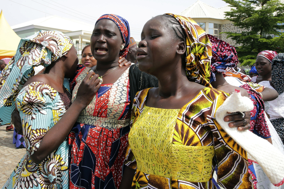 Family members react as they embrace a relative, one of the released kidnapped schoolgirls, in Abuja, Nigeria, Saturday,